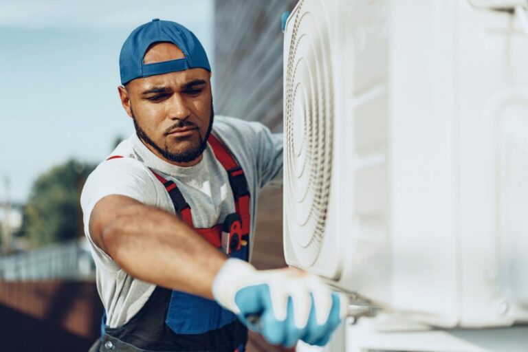 young black man repairman checking an outside air conditioner unit 768x512